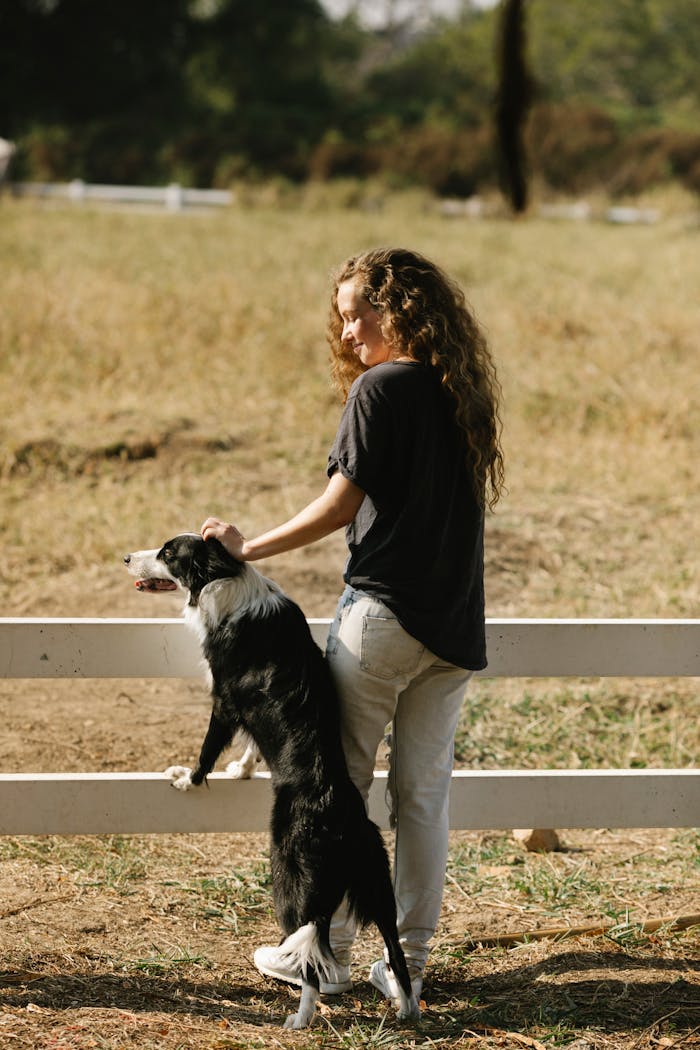 Girl and Dog Standing Together at Farm Fencing